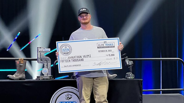 A male contestant holds a check after winning a challenge at an Elite Trades Championship Series competition, open to construction students at Western New York Works colleges.