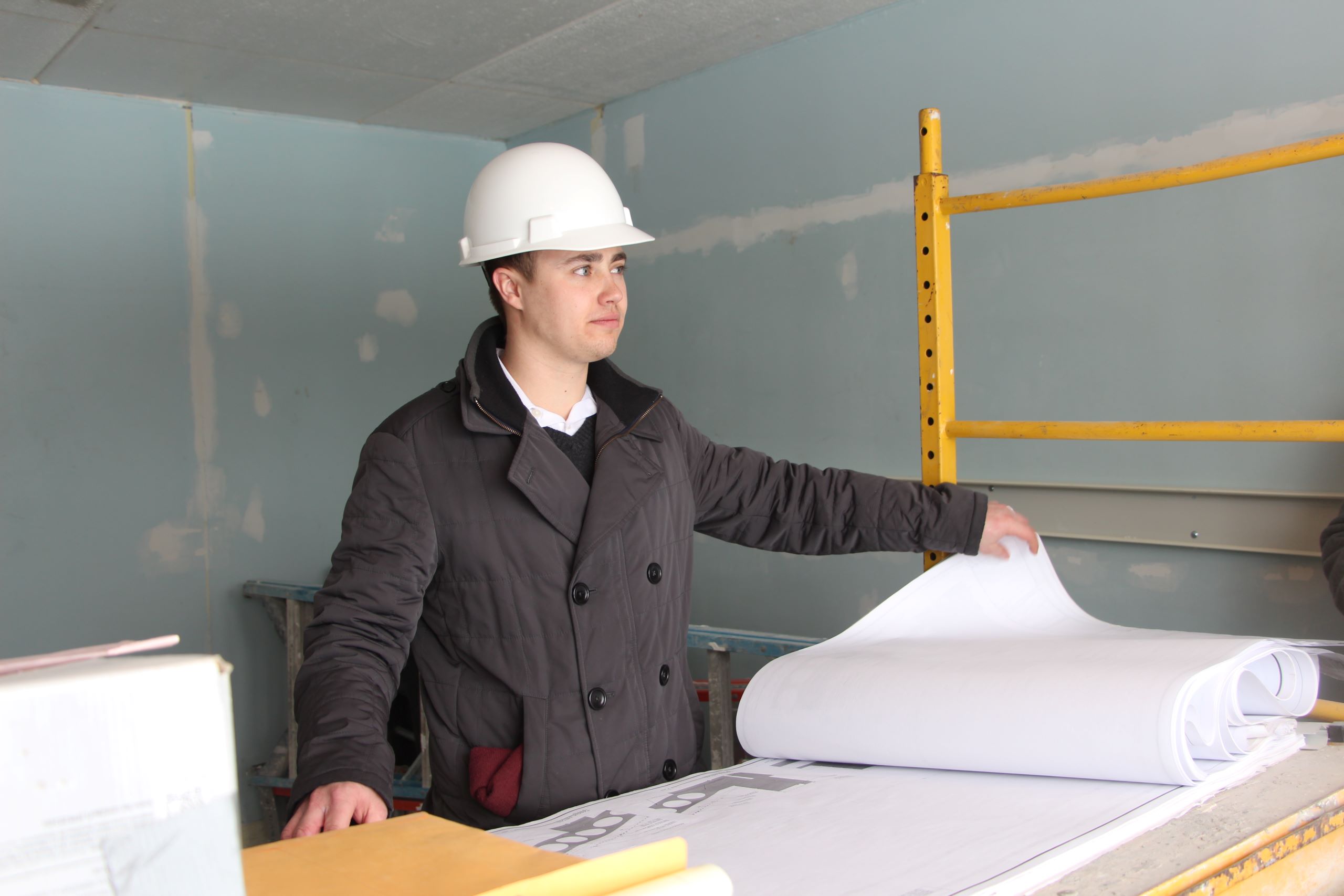 A student wearing a hard hat flips through blueprints in a class for a construction career training program at a Western New York Works college.