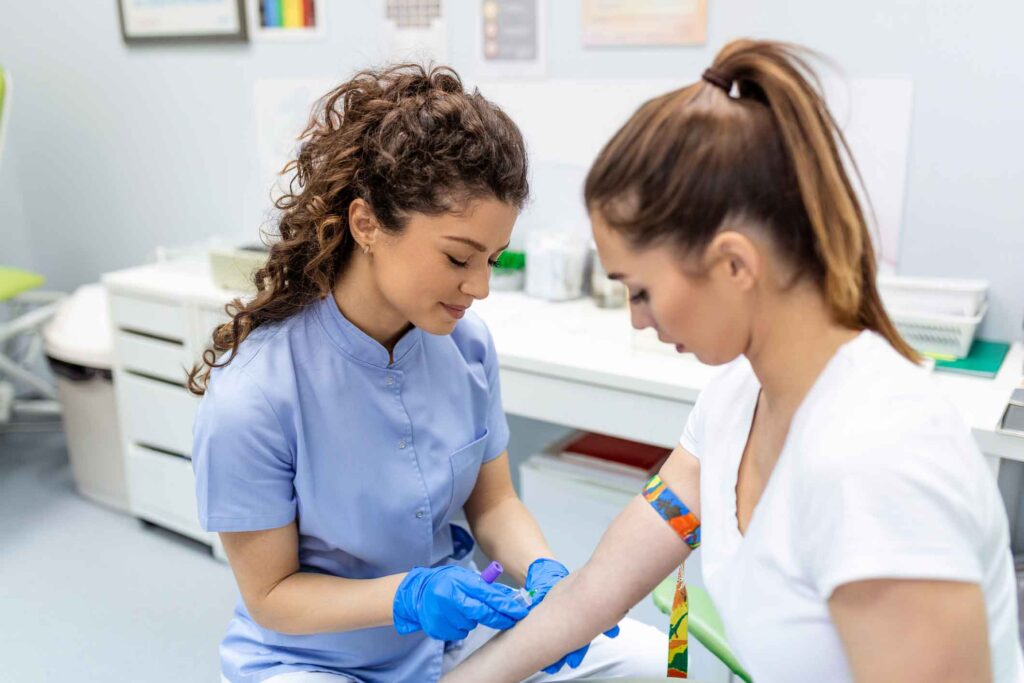 A phlebotomy student at a Western New York Works college wears gloves to practice finding a vein on another student.