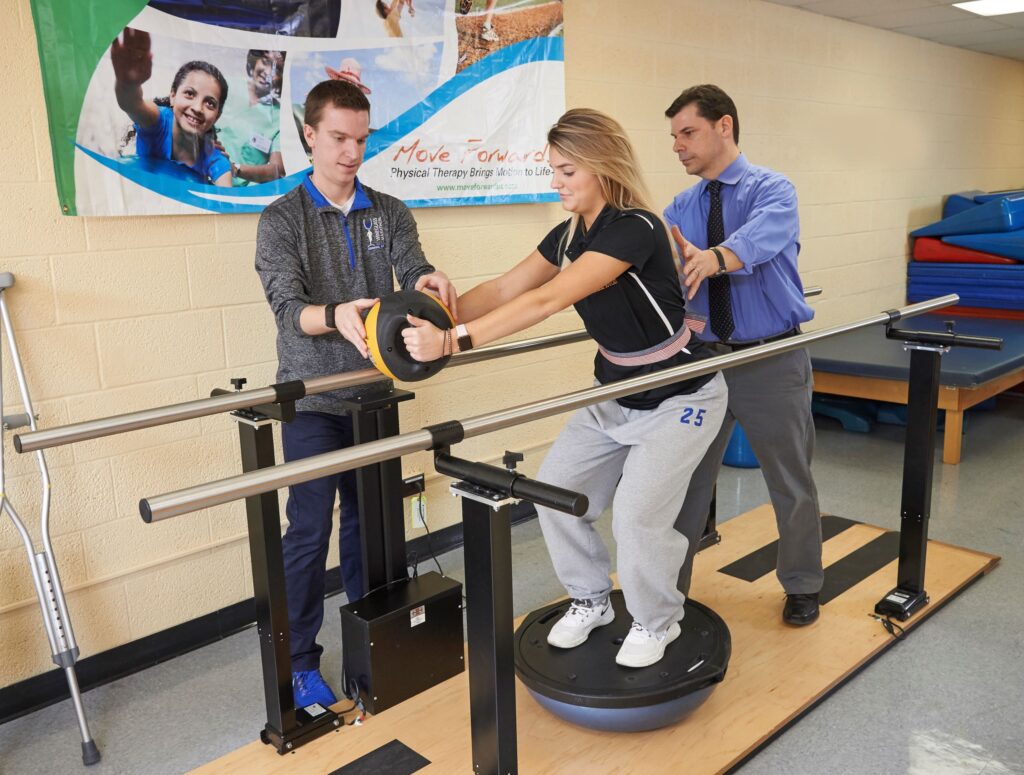 Two physical therapy assistant students plus an instructor practice patient exercises in a training space at a Western New York Works college