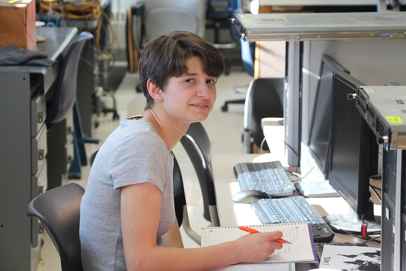 A student with a notebook sits in front of a computer in campus lab at a Western New York Works college.