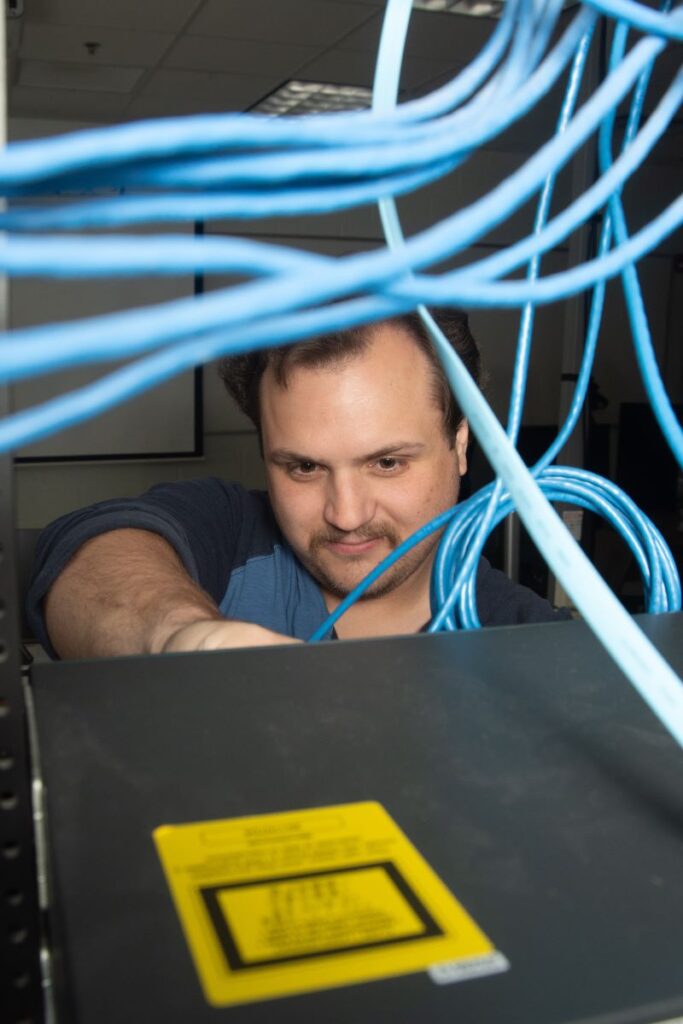 A male student gets hands-on experience working with networking equipment in a Western New York Works information technology career training program.