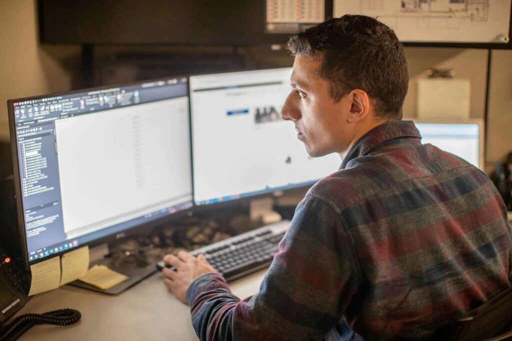 A student sits at a desk with two monitors in a web design class at a Western New York Works college.